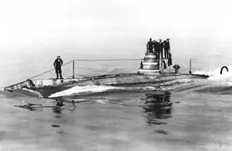 A black and white photograph of a submarine with multiple men on its tower