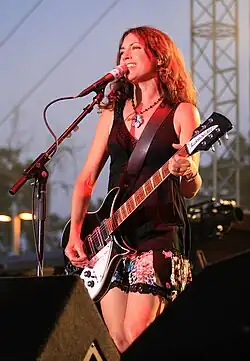 A woman playing a black and white electric guitar.