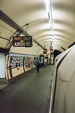 An underground station platform with curved walls and ceiling. A train is alongside the platform.