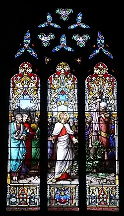 A three-segmented stained glass window featuring biblical figures (including Zaccheus) and decoration.