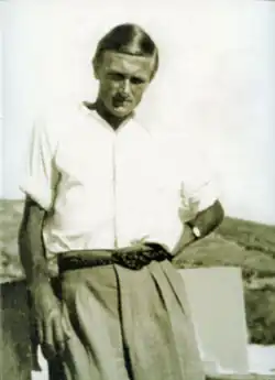A young archaeologist, in shirt sleeves and trousers, at an archaeological site.