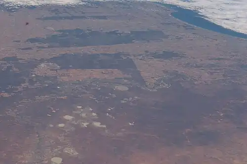 View of MacCabe Corner (red circle) from the International Space Station, facing south. The Victoria–South Australia border is visible as a straight line, with dark uncultivated land in Victoria on the left (east) and light-coloured arable land in South Australia on the right (west). The Murray River runs through the centre. The NSW–SA border (lower part of image) is not visible from the air as both areas are nature reserves. Encounter Bay is at upper right.