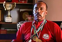 Majed Abu Maraheel in an interview, wearing three medals with a trophy in the background