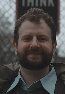 Headshot of a man with curly hair.