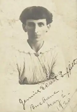 Photograph of a woman with bobbed hair wearing a striped dress with a wide, white, scalloped collar adorned with a broach at the base of her neck.