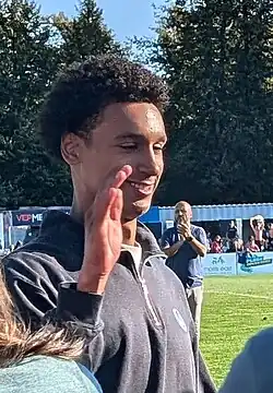 Profile of Kareem Sow smiling and raising his left hand to high five someone