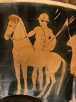 Castor, standing behind a horse, wearing a helmet