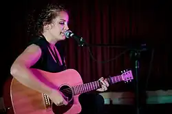 Loder singing and playing acoustic guitar onstage