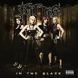 Four women dressed in gothic clothing in a forest. The text "Kittie" at the center top, with "In the Black" at center bottom