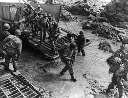 U.S. soldiers getting off their landing craft onto the rocky shores of Kiska Island