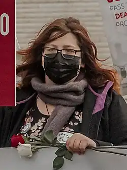 Handy attending a protest in January 2022, holding a red sign and roses while standing in front of the US Supreme Court Building in Washington, D.C.