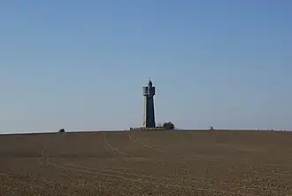 A folly on a hill in a ploughed field