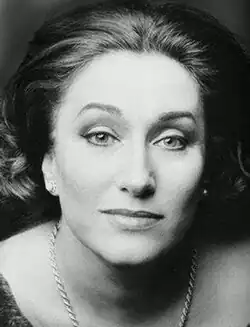 Black and white publicity shot of half-smiling woman in full make-up, with bouffant, straight, dark, shoulder-length hair, combed back