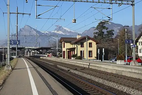 Double tracks, platforms, and a yellow two-story building
