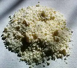Pile of cream-colored granules on a table. Some are clumped together.