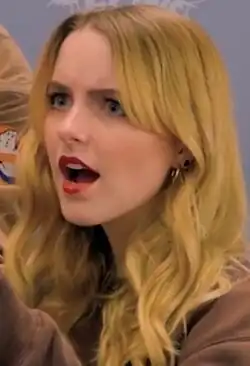 Mckenna Grace in a brown sweater against a blue background at the 2023 German Comic Con in Dortmund