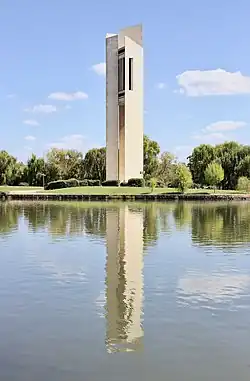 A large white brick tower standing by a lake