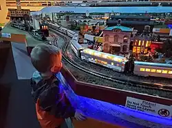 Boy watching toy train pass on train layout.