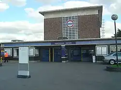 A red-bricked building with a rectangular, dark blue sign reading "NORTHFIELDS STATION" in white letters all under a light blue sky