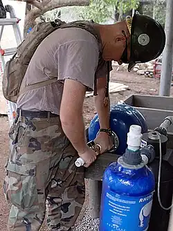 A utilitiesman attaching a water purifier to a water pump in Canton El Sunza
