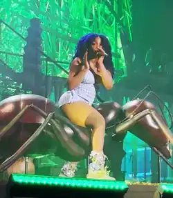SZA in a 2024 concert, singing on top of a large ant prop