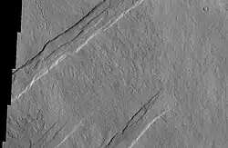 Oti Fossae, as seen by THEMIS. These parallel graben are found on the northeastern side of Arsia Mons; they are in line with the NE/SW trend of the three volcanoes in Tharsis.