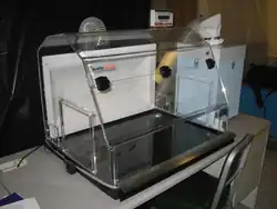 A clear plastic box on a desk with clear tubes emerging from its top