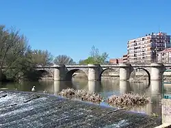 Photo depicts a stone bridge with five arches crossing a river.