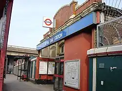 A brown-bricked building with a rectangular, dark blue sign reading "ROYAL OAK STATION" in white letters all under a light blue sky
