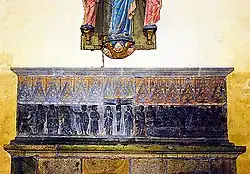 Photo showing a stone altarpiece on a wall.