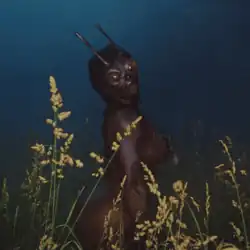 Cover art for "Drive": SZA dressed in a full-body insect costume, using black body paint and a prosthetic mask