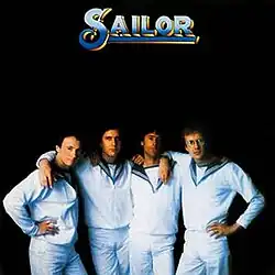 A blue logo written as "SAILOR", above four men dressed as sailors in a dark background
