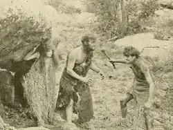 Black and white film still showing prehistoric scene