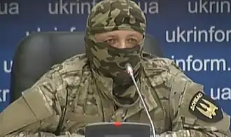 A seated, uniformed soldier with only his eyes and nose showing