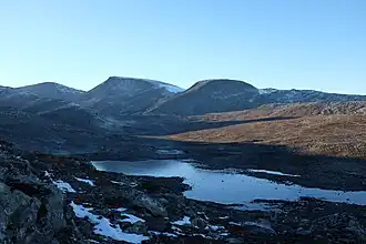 A lake beside partially snow-covered mountains