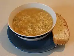 a bowl of brown coloured soup with egg white flecks