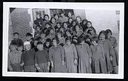 Group photo of Indigenous students in front of a brick building. A nun is visible in the back row.