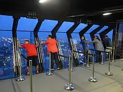 2014 dusk interior view of tourists on the TILT Thrill Ride, with the attraction in its outward-leaning position