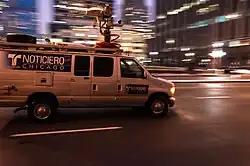 A white microwave news van with blue graphics reading "Noticiero Telemundo Chicago" on the streets of Chicago