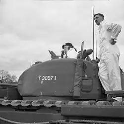 A photo showing Winston Churchill speaking into a radio while poking out of a turret of a Churchill tank.