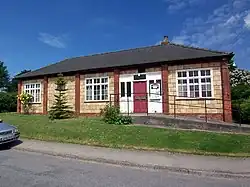 Parish Hall, a single story building with a hipped roof and tiled walls