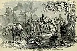 a group of African Americans, one riding a donkey walking to the left, being met by two Union Soldiers on the right who are facing them. There is a tree on the right with two other Union around it.