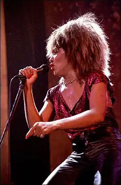 Turner holding a microphone during a performance on stage with a sparkle top