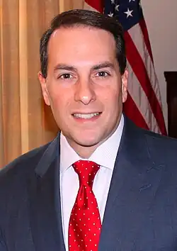 Tom Basile smiling for a photo, wearing a business suit
