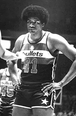 A black-and-white photo of a black man wearing a red, white, and blue uniform that says "Bullets" on it with the number 41 worn.
