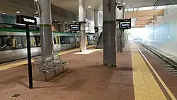 Train station platform underneath a large concrete concourse