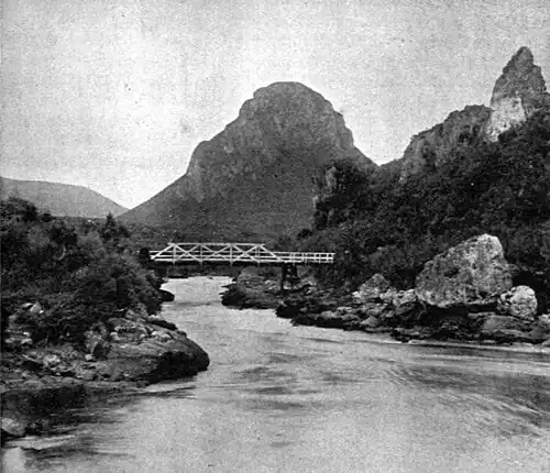 River with a bridge, surrounded by bush with hills in the background