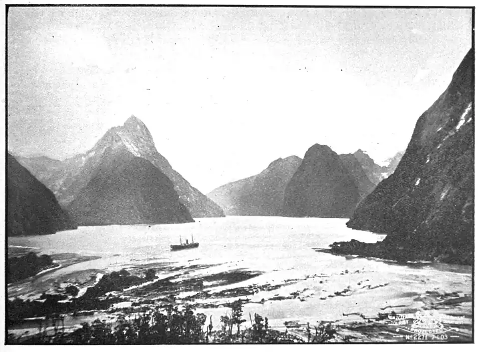 Boat on a wide expanse of water with mountains with steep slopes and a scattering of snow coming down to the water's edge