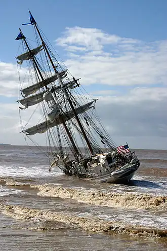A sailing ship aground on a beach
