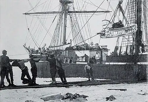 Photo of men on pack ice pulling a rope attached to a machine being hoisted out of a wooden ship